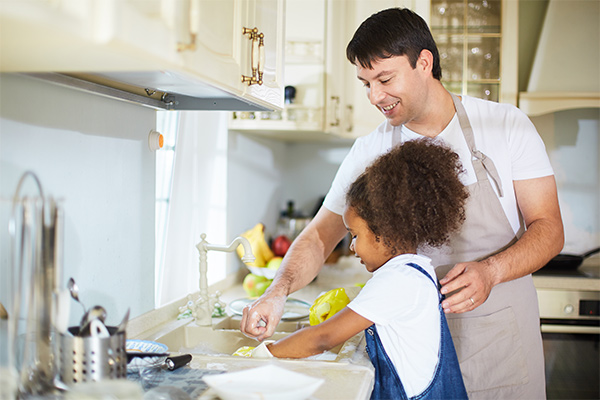 Foster dad doing dishes with young girl