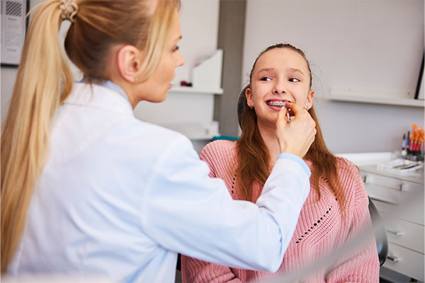 Orthodontist checking braces on girl's teeth