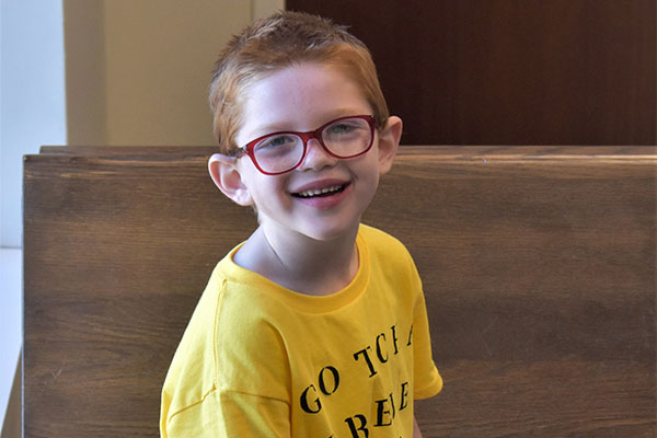 smiling little boy with glasses and yellow shirt
